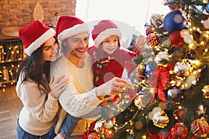 Happy family decorating Christmas tree with bubbles in living room