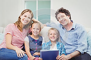 Happy family with digital tablet sitting on sofa