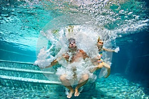 Happy family diving underwater with fun in swimming pool