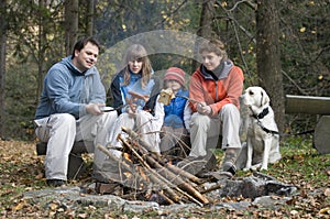 Happy family with dog near campfire