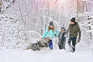 Happy family with dog outdoors in a winter forest. Mother, fother, son and big pet dog.