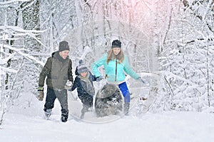 Happy family with dog outdoors in a winter forest. Mother, fother, son and big pet dog.