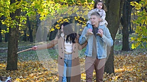 Happy family with dog walk on autumn leaves