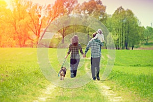 Happy family with dog walking on the rural dirt road