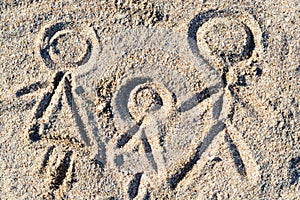 Happy family drawing on sand in the summer