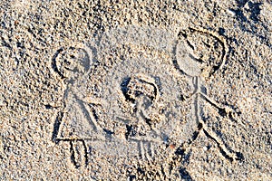 Happy family drawing on sand in the summer