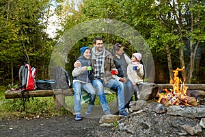 Happy family drinking hot tea near camp fire