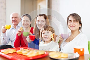 Happy family drinks tea with cakes