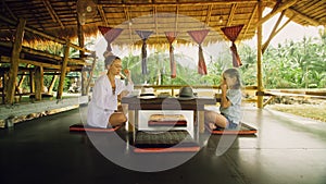 The happy family eat and drink tasty beverages spending time in local floating cafe on water. Mother and daughter having