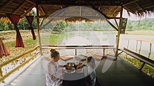 The happy family eat and drink tasty beverages spending time in local floating cafe on water. Mother and daughter having