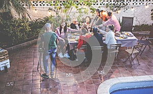 Happy family eating and cheering with red wine at barbecue party dinner - Different age of people having fun at bbq meal sitting