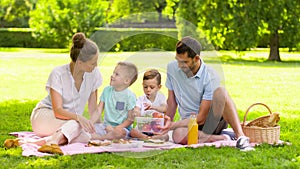 Happy family eating fruits on picnic at park