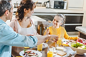 happy family eating pancakes at table with juice and fruits
