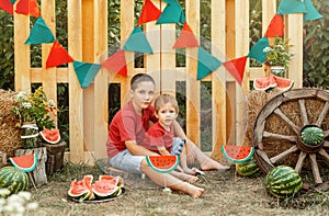 Happy family eating watermelon in the garden. Kids eat fruit outdoors.