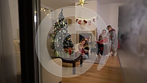 A happy family, an elderly couple, their daughter and little grandson and a dog have fun by the fireplace on Christmas