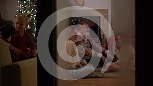 A happy family, an elderly couple, their daughter and little grandson and a dog have fun by the fireplace on Christmas