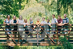 Happy family of eleven standing on bridge in park