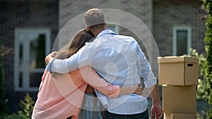 Happy family embracing, moving in new house, long-awaited purchase, back view photo