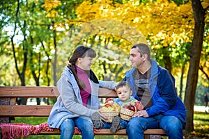 Happy family enjoying autumn picnic. Father mother and son sit o