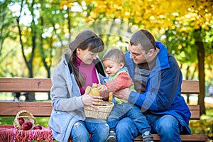 Happy family enjoying autumn picnic. Father mother and son sit o