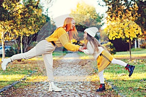 Happy family enjoying autumn weather in the park. Lovely girl with her mom having fun on the walk