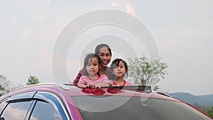 Happy family enjoying road trip on summer vacation. Mother and child enjoying nature along the way in the car on sunroof. Holiday