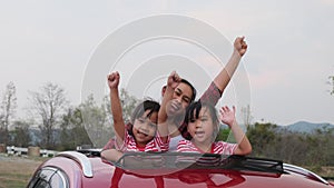 Happy family enjoying road trip on summer vacation. Mother and child enjoying nature along the way in the car on sunroof. Holiday