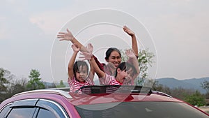 Happy family enjoying road trip on summer vacation. Mother and child enjoying nature along the way in the car on sunroof. Holiday