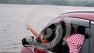 Happy family enjoying road trip on summer vacation. Mother and children are excited and enjoy traveling by car and looking out the