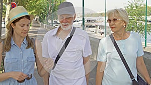 Happy family enjoying vacation. Seniors and their daughter having great time walking along promenade