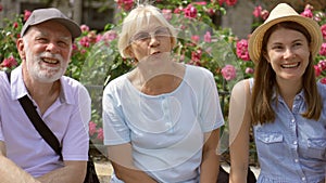 Happy family enjoying vacation. Seniors and their daughter sitting on bench on street relaxing