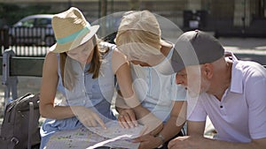 Happy family enjoying vacation. Seniors and their daughter studying city map looking for showplaces
