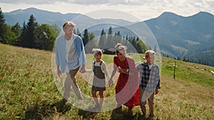 Happy family enjoying walk in mountains. Couple with kids holding hands outdoor.