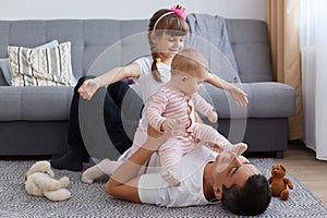 Happy family enjoying weekend together, lying on floor and having fun, people wearing casual style clothing, posing in living room