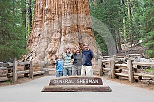 Happy family enjoys posing in sequoia national park in fromt of general sherman sequoia tree photo