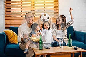 A happy family enjoys the thrill of a football match at home