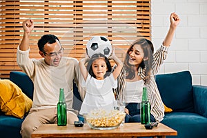 A happy family enjoys the thrill of a football match at home