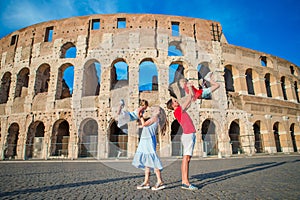 Happy family in Europe. Parents and kids in Rome over Coliseum background.