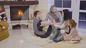 Happy family exchanges christmas gifts near fireplace