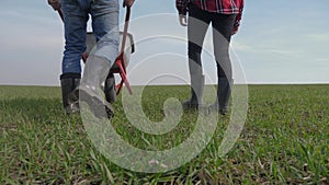 Happy family of farmers teamwork red neck works in the field with a garden trolley in rubber boots. man and girl farmer