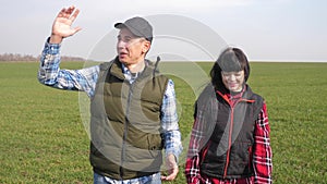 Happy family of farmers teamwork a red neck works go on the green field. man and girl farmer are studying eco lifestyle