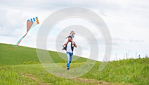 Happy family father and baby daughter run with kite on meadow