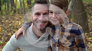 Happy family father and child boy in the autumn leaf fall in park close together