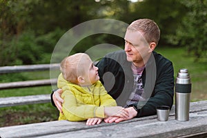 Happy Family: Father And Child Boy Son Playing And Laughing In Autumn Park, Sitting On Wooden Bench And Table. Father