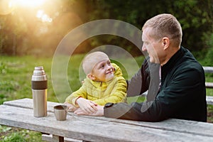 Happy Family: Father And Child Boy Son Playing And Laughing In Autumn Park, Sitting On Wooden Bench And Table. Father