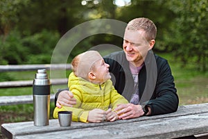 Happy Family: Father And Child Boy Son Playing And Laughing In Autumn Park, Sitting On Wooden Bench And Table. Father