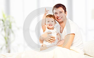 Happy family father and child daughter playing in bed