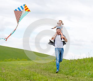 Happy family father and child daughter run with kite on meadow