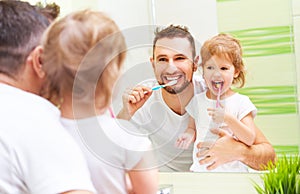 Happy family father and child girl brushing her teeth in bathroom toothbrushes