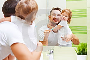 Happy family father and child girl brushing her teeth in bathroom toothbrushes